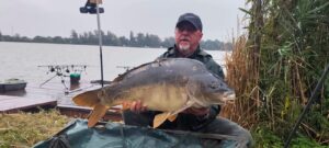 Zawodnik zawodów Jesień z Carp Servis Václavík prezentuje złowionego karpia podczas jesiennego karpiowania